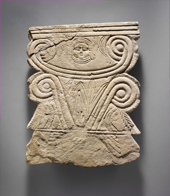 Limestone funerary stele with volutes and a Hathor head