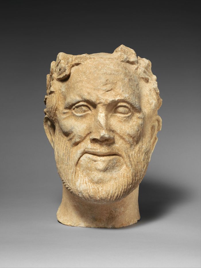 Limestone head of bearded male votary with wreath of leaves