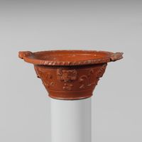 Terracotta statuette of a male figure holding the head and neck of a mask or image
